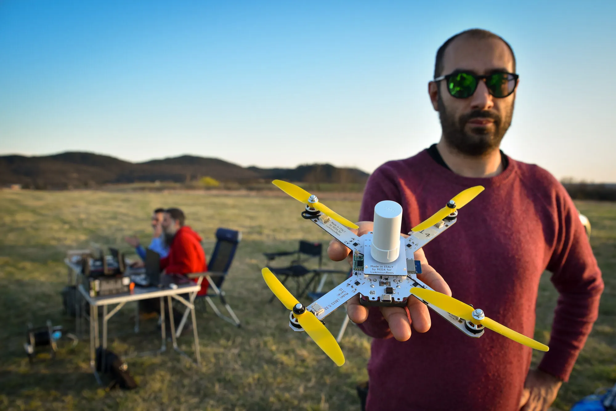 Giorgio Rinolfi holding a LuminousBee drone with the team in the background